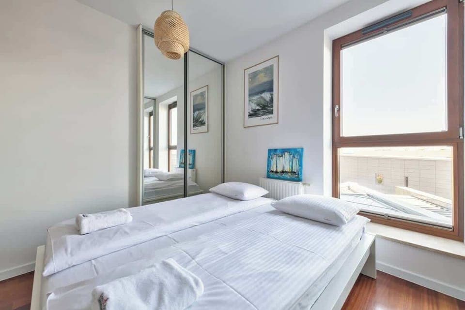 A serene bedroom with a comfortable double bed, large windows, and soft, neutral decor to enhance relaxation.