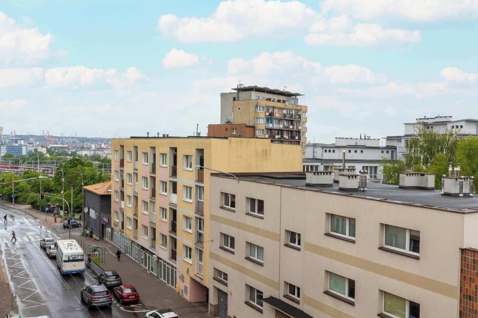 A higher perspective captures the rooftops of residential buildings and the surrounding green areas under a partly cloudy sky.