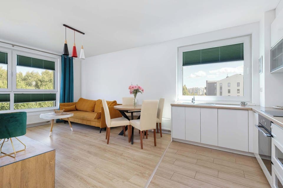 Living space featuring a sofa, coffee table and a dining table set for 4, blending functionality and style.