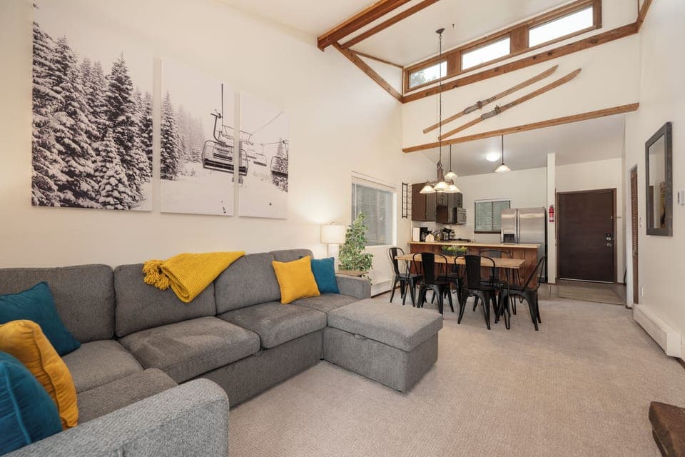 Relax in your open-concept living space with soaring wood beam ceilings and cozy sectional seating, perfect for unwinding after mountain adventures.