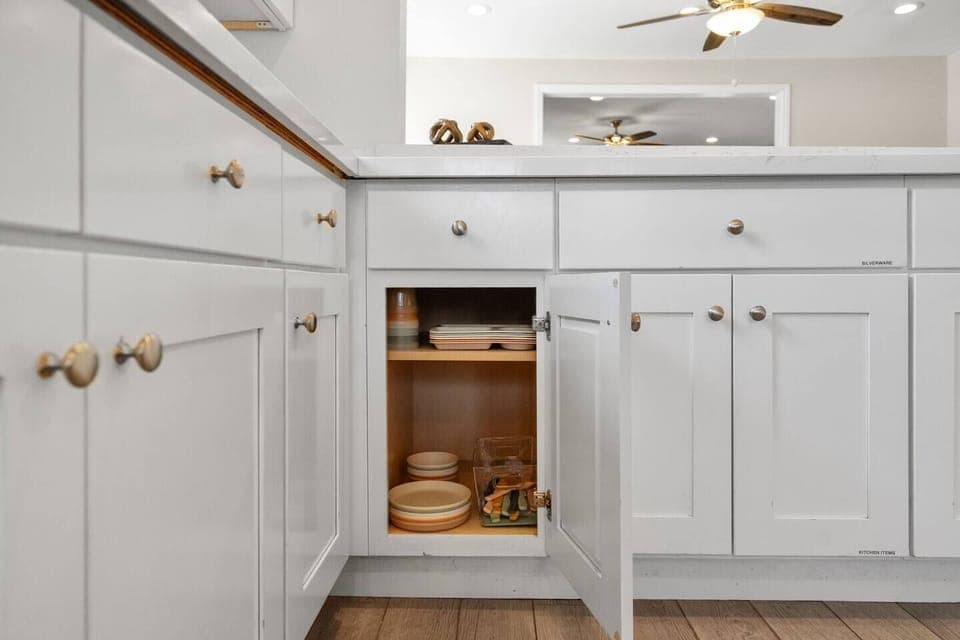 Modern cabinet reveals tidy shelves with dishes and trays for guest cooking ease