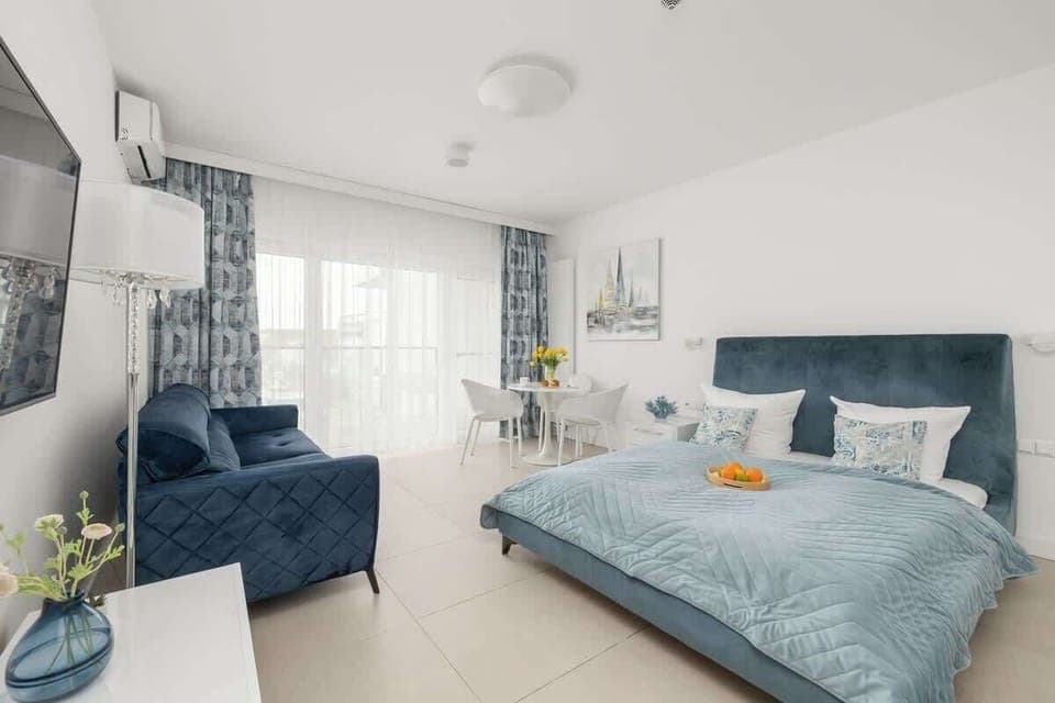 A cozy living room space with a stylish sofa bed and a TV area for relaxing evenings. Light-toned walls and modern decor create a fresh and inviting atmosphere.