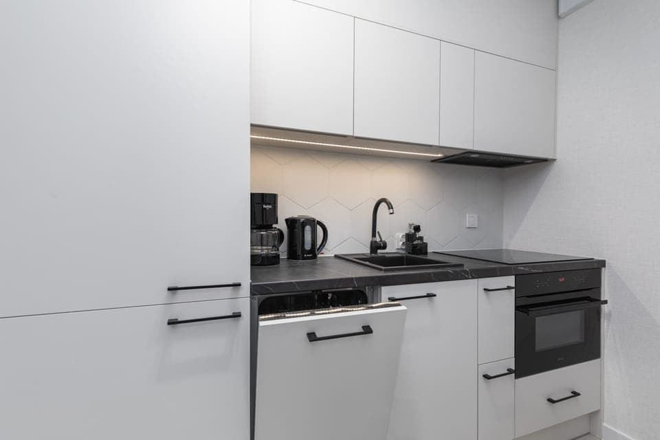 A close-up of the modern kitchen and counter, equipped with a sink, stove, and elegant black fixtures.