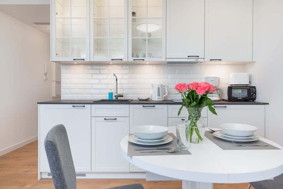 A dining space with a round white table set with plates and cutlery, surrounded by comfortable chairs.