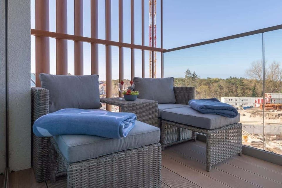 A view of the balcony showcasing a seating area with chairs and a small table, overlooking a scenic urban environment.