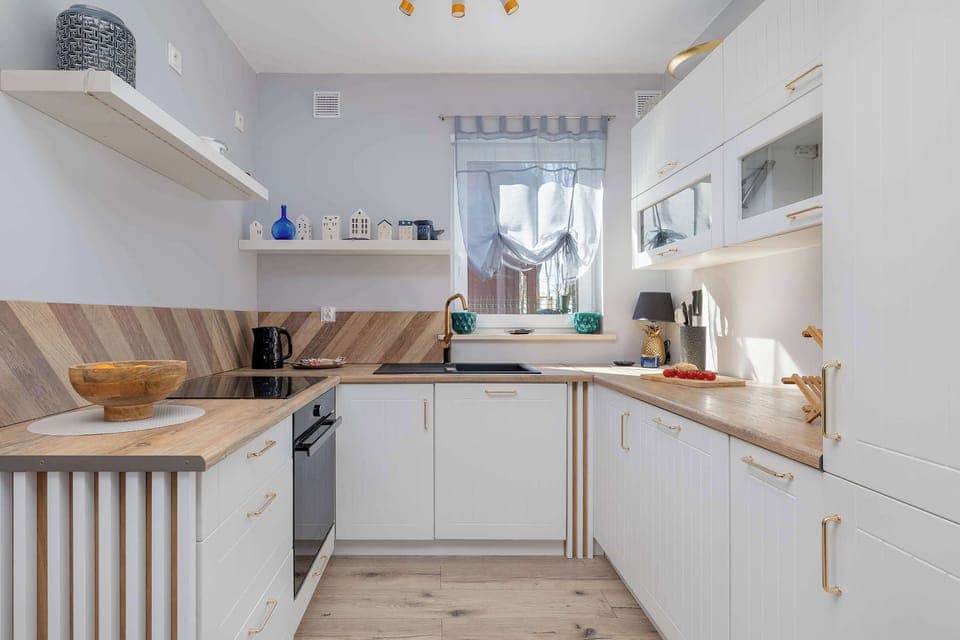 Charming kitchen awaits you - white with wooden accessories, exuding warmth and brightness, ideal for cooking together and spending time with loved ones. This is a place where the harmony of elegance will allow you to fully feel the seaside climate!