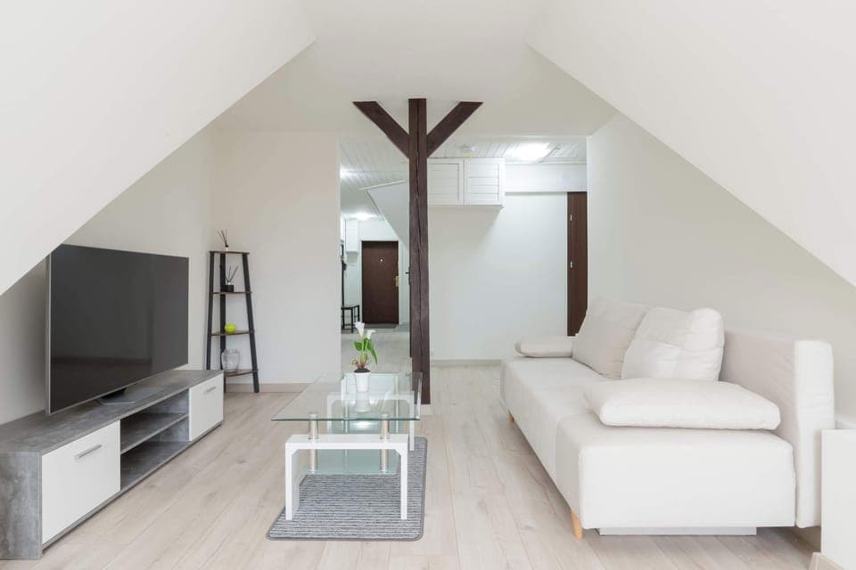 A modern living room with a white corner sofa, a glass coffee table and a large TV mounted on a low RTV cabinet just in time for relaxation. 