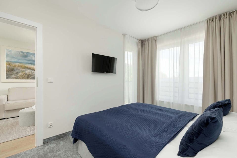 Stylish bedroom with soft textiles and a mounted TV for evening entertainment. The decor is simple and restful.