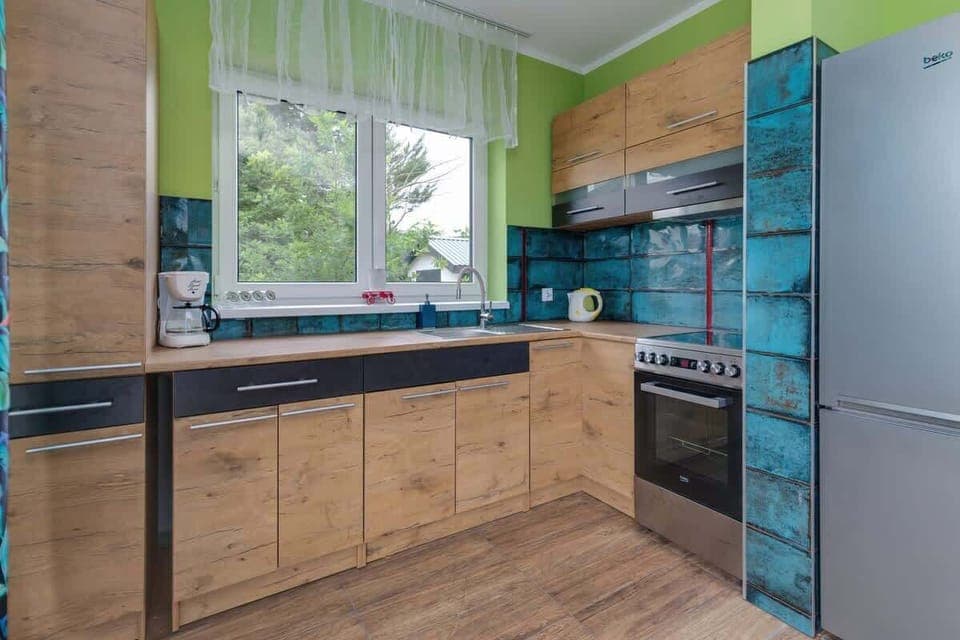 A modern kitchen with wooden cabinetry, a bright green accent wall, and a stylish design.

