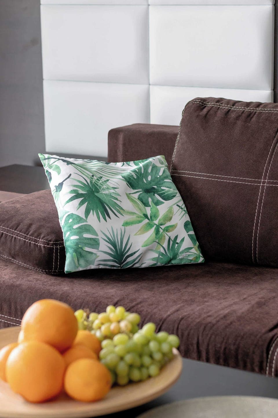 A stylish living area with a sofa, throw pillows, and a bowl of fruit. Designed for comfort and visual appeal.