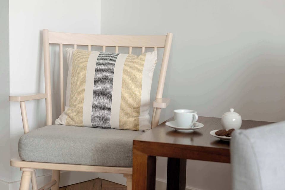 A living room detail featuring a beige couch, striped pillows, and a coffee tray. Inviting atmosphere for relaxation.