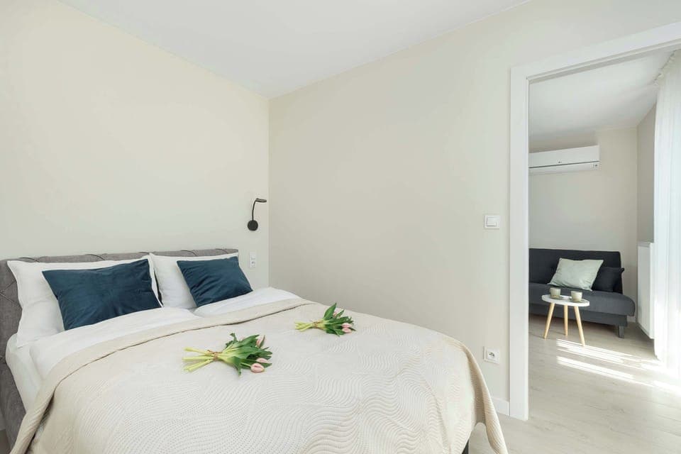 A cozy bedroom with a double bed, bedside tables, and natural light. The decor is simple yet elegant.