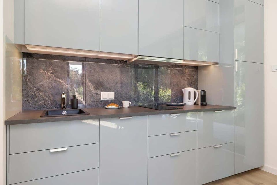 Practical, elegant kitchenette with glossy cabinets, black countertop ideal for cooking.