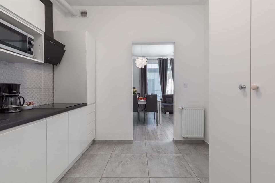 A sleek and modern kitchen with white cabinetry, a black countertop, and ample space for meal preparation.
