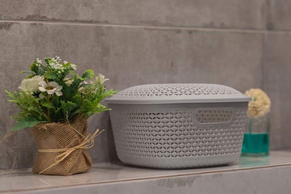 A decorative bathroom setup featuring a modern basket and fresh flowers for a cozy ambiance.
