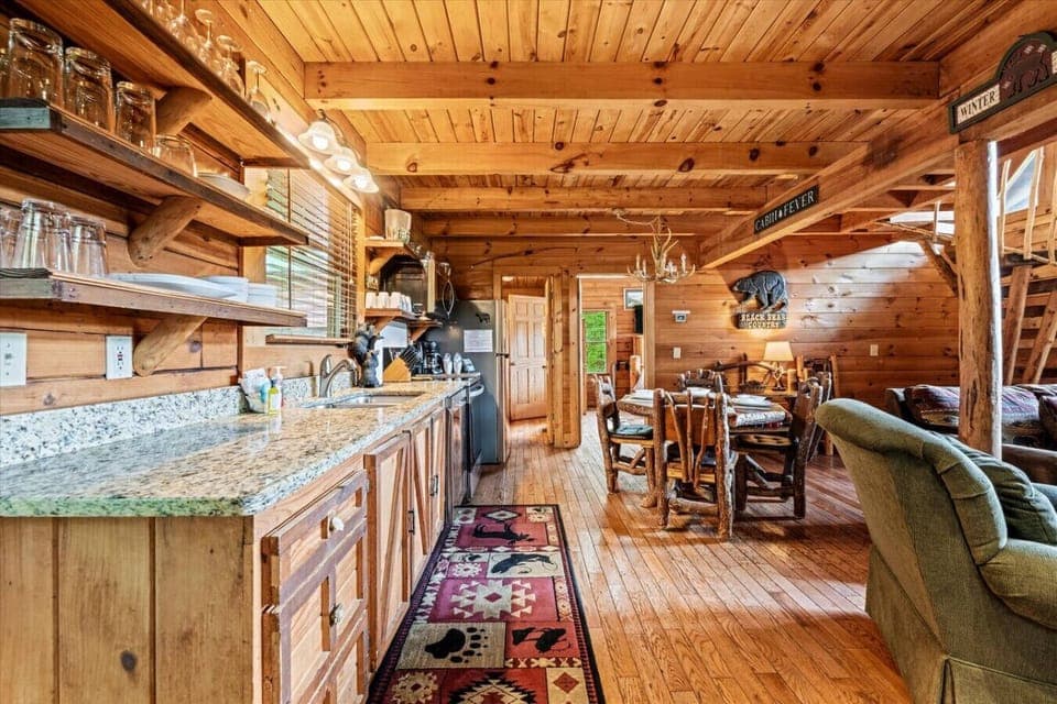 Enjoy family-style dining at the log-crafted table beneath an antler chandelier, a cozy nod to Smoky Mountain charm.