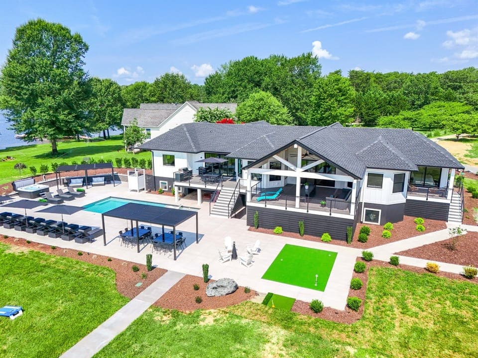Aerial view of the resort-style amenities - private pool, 8-person hot tub, putting green, covered porch and walkways to the lake