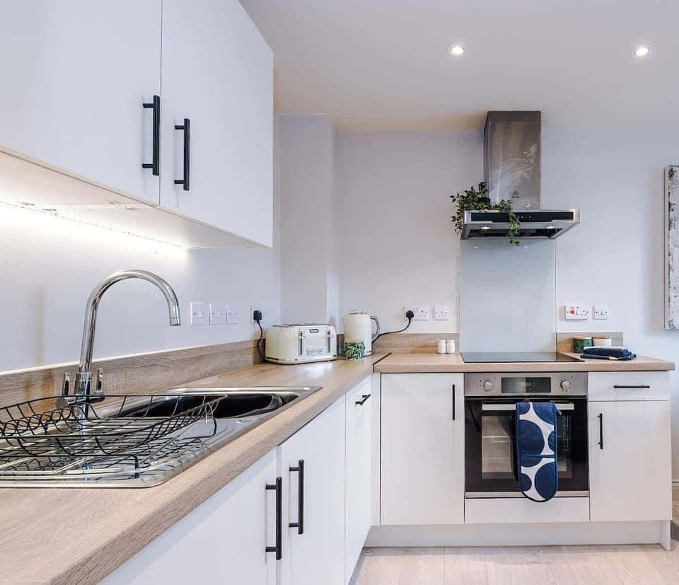 Modern kitchen equipped with a stovetop, microwave, toaster, and kettle—everything you need for a quick meal or morning coffee.
