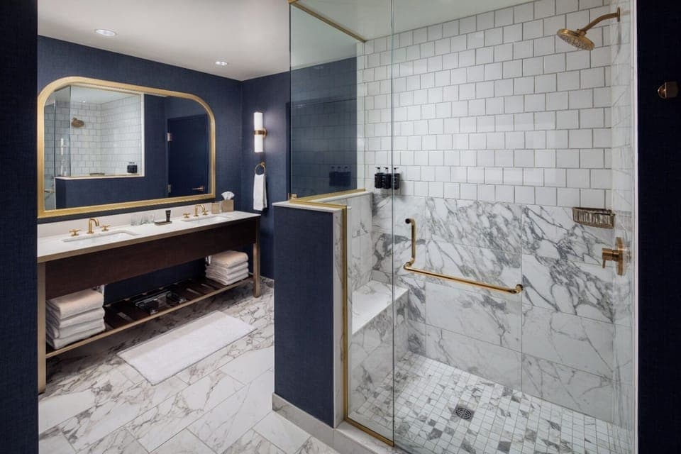 Large bathroom with walk-in shower with seat and two sinks.