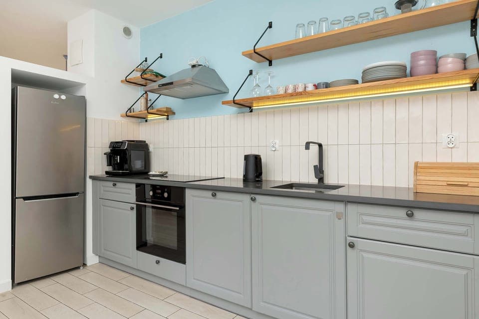 Modern kitchen with pastel blue cabinets, open shelves, and full appliances.