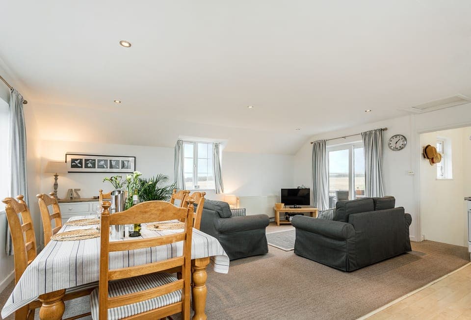 Arnold Cottage in Treyarnon Bay. First-floor openâ€‘plan living, dining and kitchen area with sofa bed and seaâ€‘view window