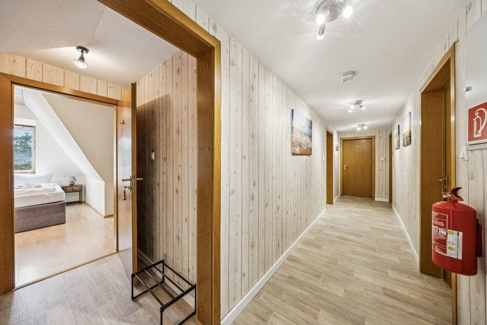 Heller Flur mit Holzdekor, modernen Deckenleuchten und offenem Zugang zum Schlafzimmer – einladender Bereich der Ferienwohnung.