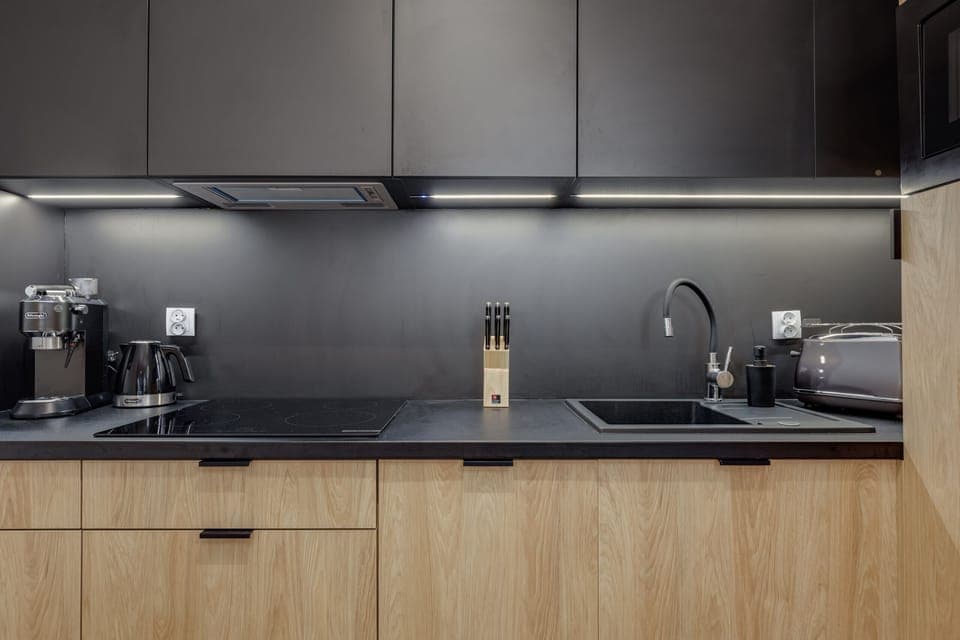 A modern kitchen with sleek black cabinets, wooden accents, and state-of-the-art appliances.
