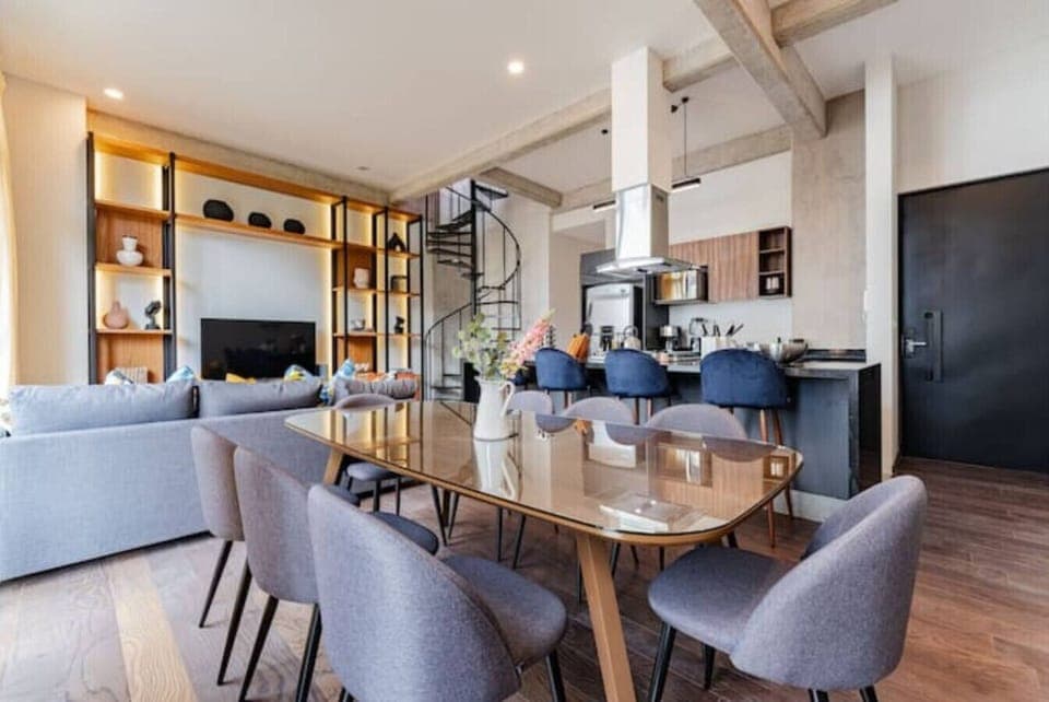 Open-concept living and dining area with a large table, unique chairs, and modern decor.