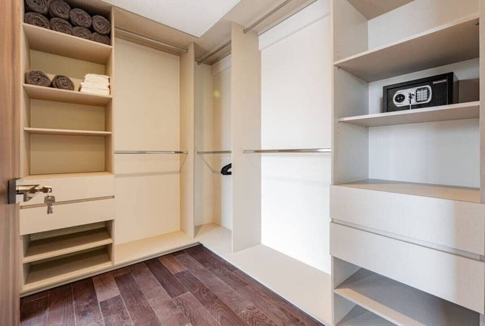 Walk-in closet with built-in shelving, drawers, and a safe.