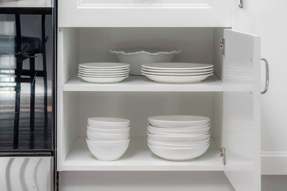 Full kitchen : Cabinet with neatly stacked plates, bowls, and glass storage containers.