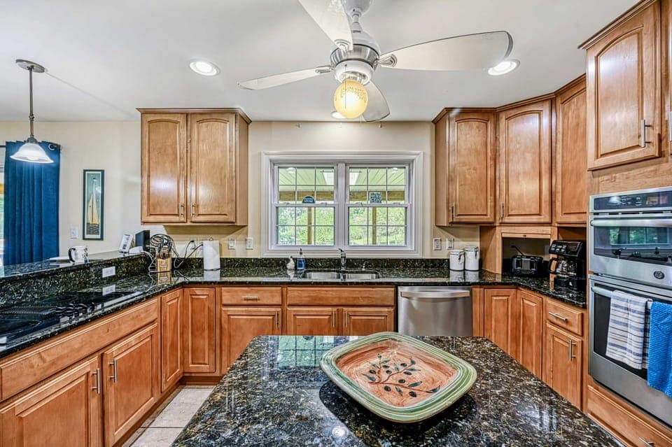Kitchen - Double wall ovens, sink with window view, and granite island in the well-equipped cooking space.
