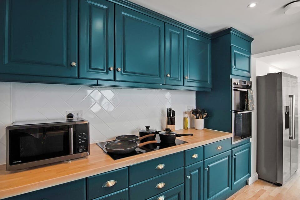 An angle of the kitchen/breakfastbar featuring the cookware and oven. All accessible during your stay