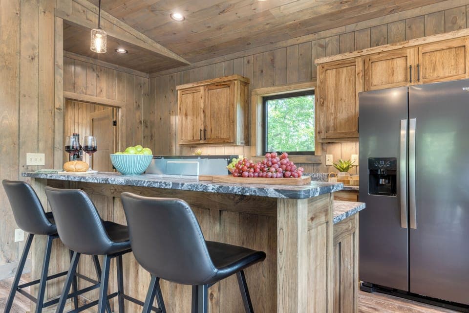 Modern kitchen with island seating and stainless steel appliances.