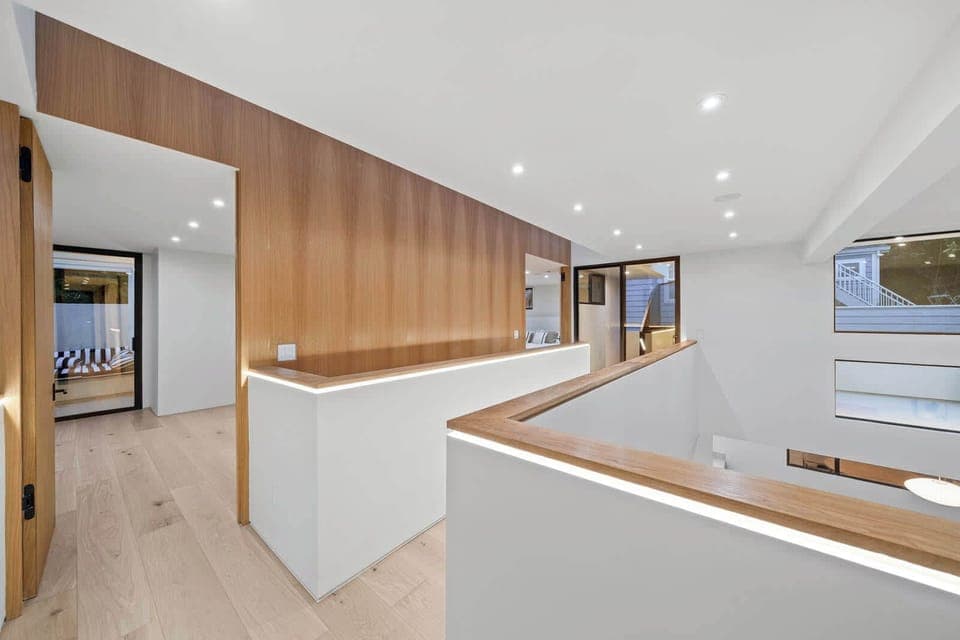 
Elegant design and natural light define this modern home. The upper hallway features beautiful wood paneling and sleek lighting, offering a stylish transition between rooms.
