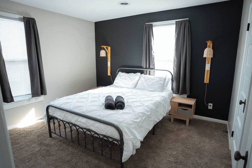 The bedroom has a comfy queen bed with fresh linens and plenty of pillows. Two nightstands with lamps make it easy to read or relax before bed. Curtains keep the space private and cozy, so you can get a good night’s rest.