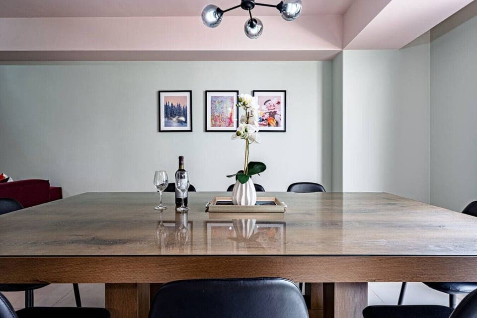 A dining table with modern wooden chairs and minimalist decor, complemented by artwork on the walls
