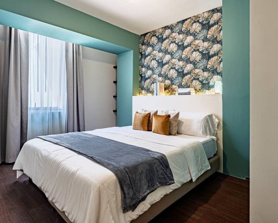 Stylish bedroom featuring a king-sized bed with crisp white linens & patterned wallpaper