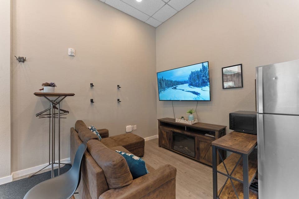 The living area offers a queen sleeper sofa and large mounted smart TV.