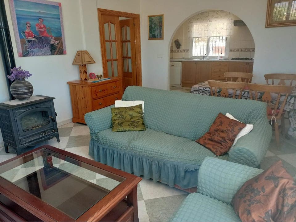 A view toward the arch leading into the kitchen; sofa, the wood-burning stove.