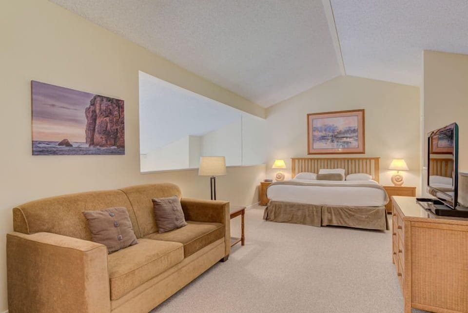 The spacious loft features a comfortable king bed, complemented by a stylish living area with a cozy couch and beautiful wall art.