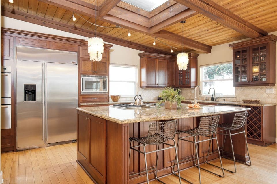 Modern kitchen with a large fridge, island, and barstool seating.