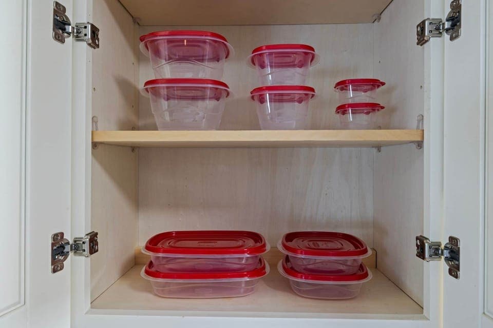 Cabinet with stacked plastic containers with red lids.