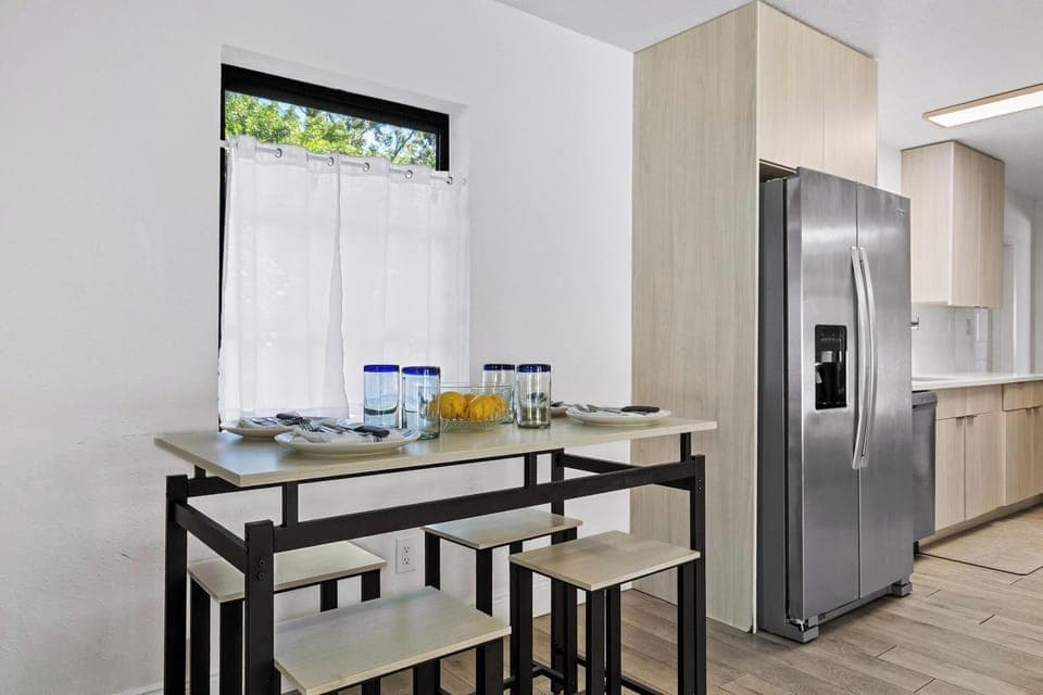 Bright and modern dining nook featuring a sleek high-top table beside the kitchen. Perfect for casual meals, morning coffee, or gathering with friends in a cozy, sunlit space overlooking the outdoors.