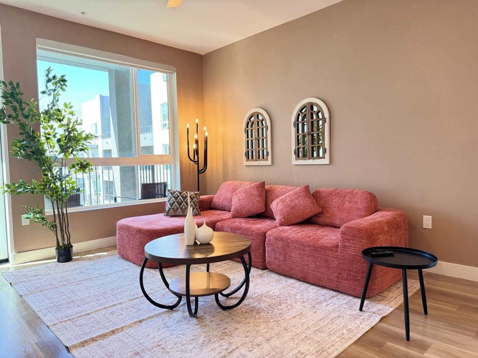 Spacious living room featuring a cozy L-shaped sofa, a full-size air mattress, and a 65" Smart TV with preloaded access to Netflix, Hulu, and Disney+, all set up for your enjoyment.