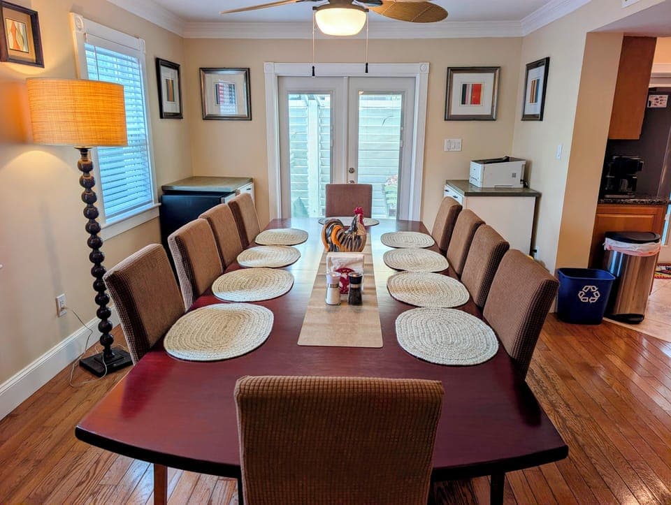 Sunny dining room for 10 with hardwoods, French doors, and ceiling fan