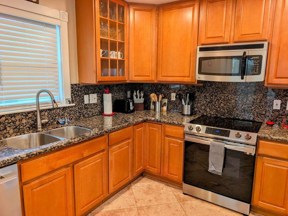 Granite kitchen with stainless range, microwave, and fully equipped.