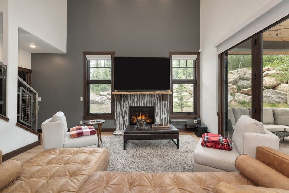 Unwind in this stylish living room where you can cozy up by the fireplace with plaid throws and enjoy mountain views.