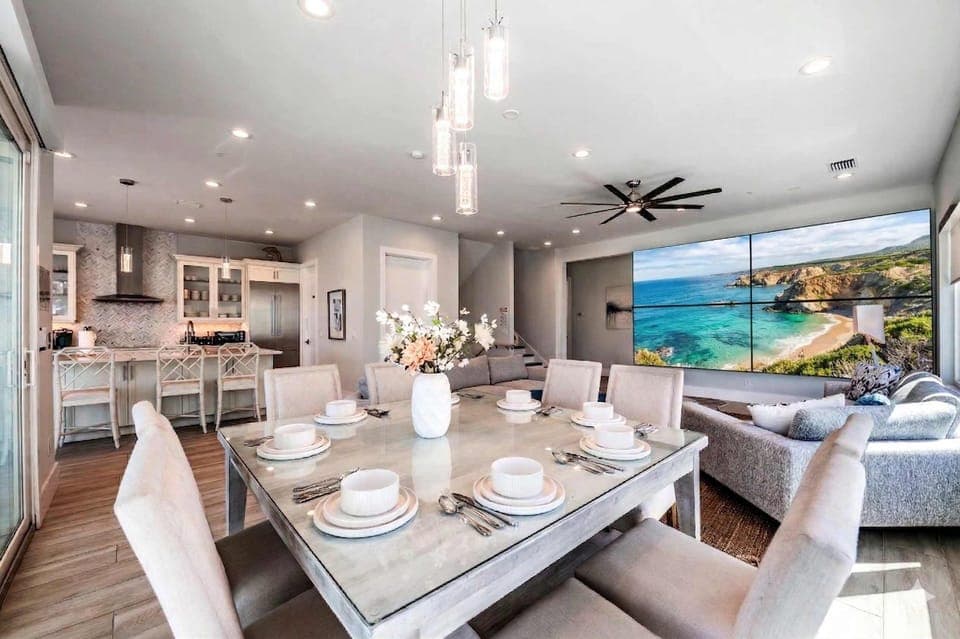 Gather in this bright, open-concept living space featuring a stylish dining area, modern kitchen, and cozy lounge with large TV. Elegant décor, ample seating, and natural light create the perfect setting for meals, relaxation, and memorable stays!