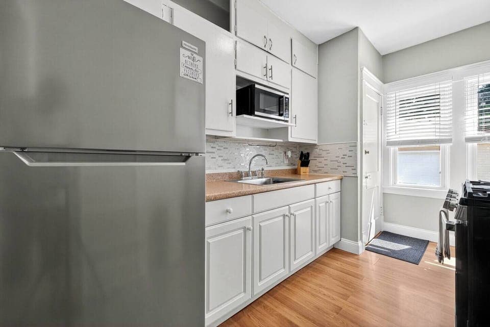 Functional kitchen setup with stove, full sink, microwave, and cooking utensils