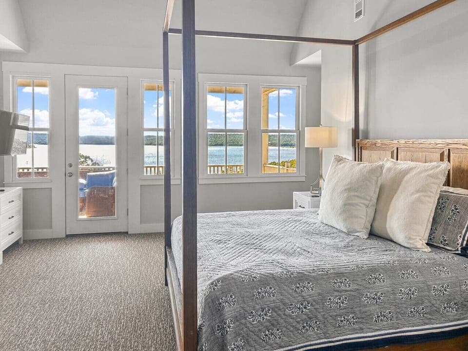 Primary bedroom with king bed, private lakeview balcony, and smart TV
